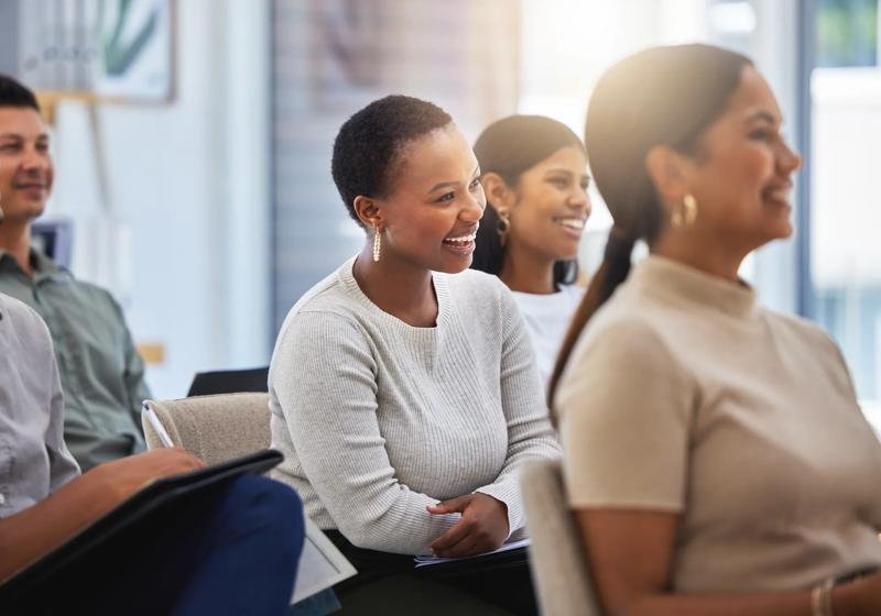 Shot of a group of employees laughing during a meeting at work in a modern office.