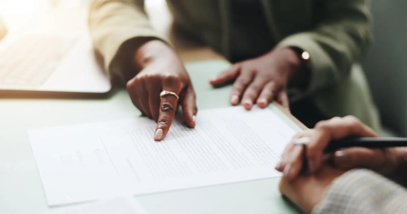 Business people, hands and pointing on contract for legal documents, application and agreement in office. Pen, closeup and person explain paperwork for policy, form or deal in workplace or company.