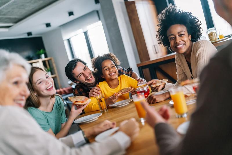 Multiethnic diverse extended family dining and toasting together with grandparents and children