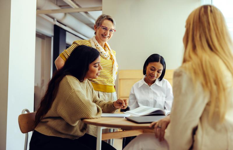 A cheerful educator interacts with students, encouraging engagement and learning in a warm and collaborative classroom atmosphere.