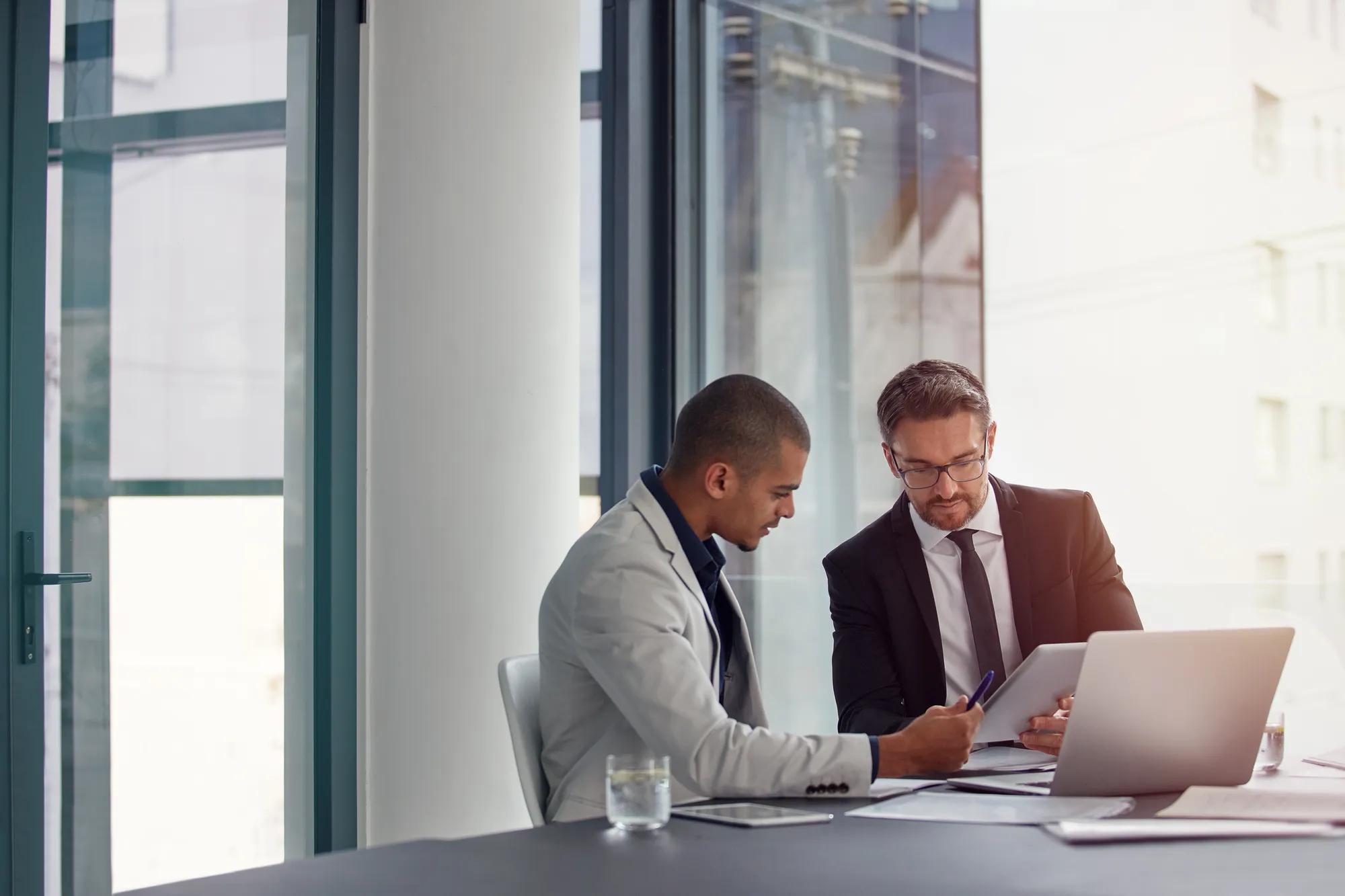 Tablet, laptop and business men planning in conference room meeting, teamwork and discussion of corporate data. Professional people or partner talking, review or report analysis on digital technology.