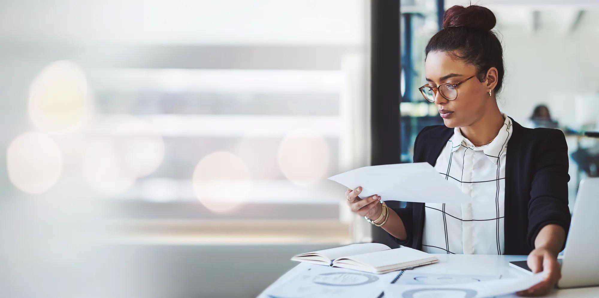 Woman analyzing health plan paperwork at a desk, reflecting employers assessing gene therapy costs, stop-loss protection, and healthcare risk management strategies.