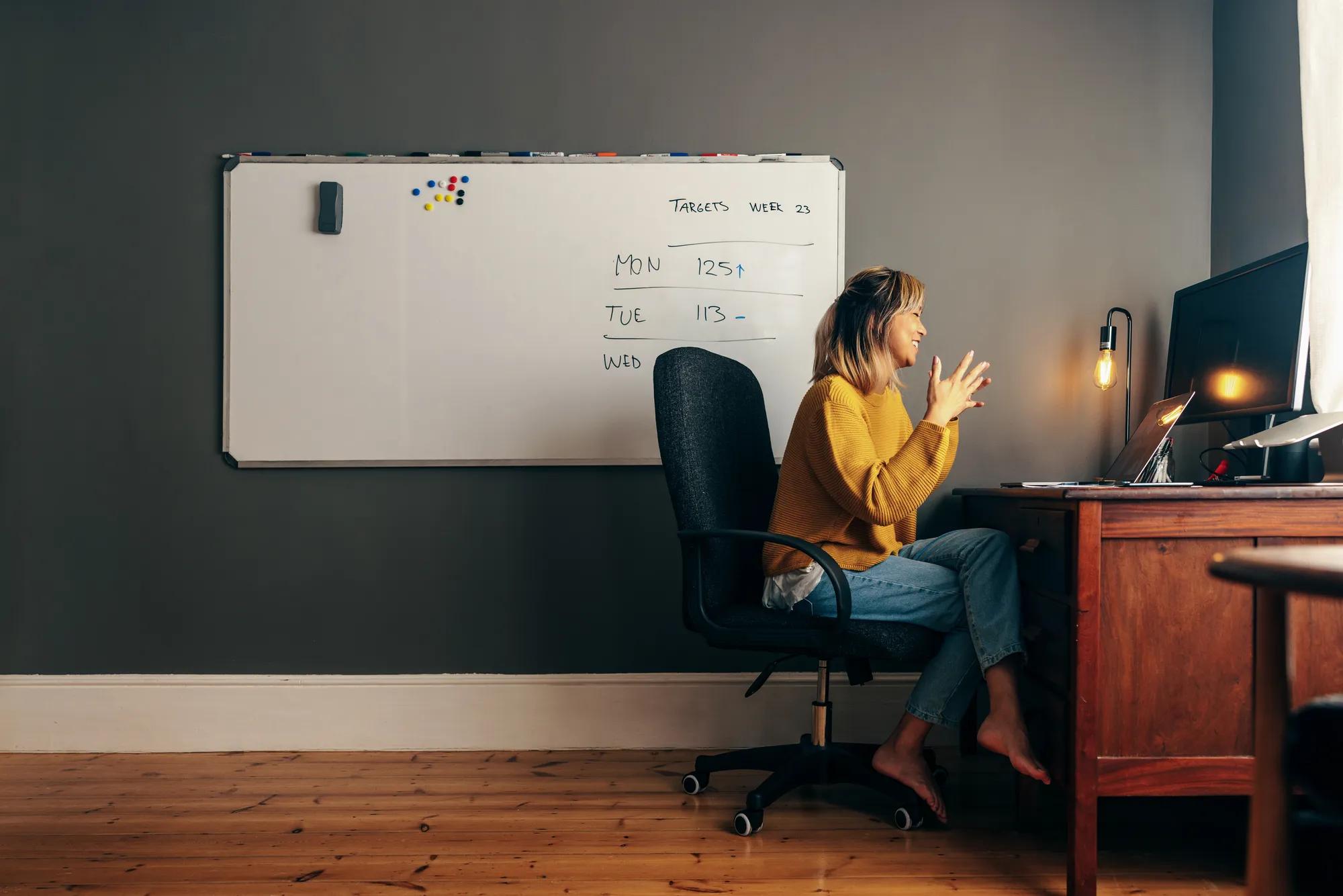 Successful businesswoman attending a virtual meeting while working in her home office. Happy female entrepreneur using a laptop to video call her business partners while working remotely.