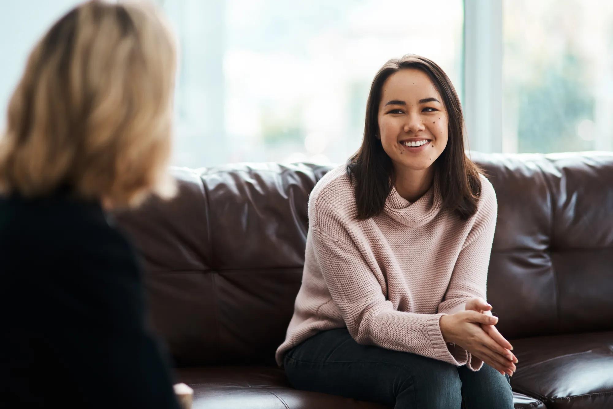Therapy, happy women have a conversation on sofa and speaking or talking with a psychologist. Mental health or communication, support or consulting and people on couch have a discussion together.
