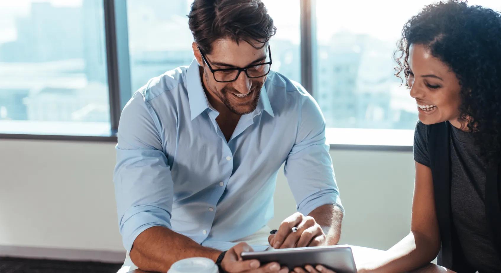 two people smiling reviewing an ipad