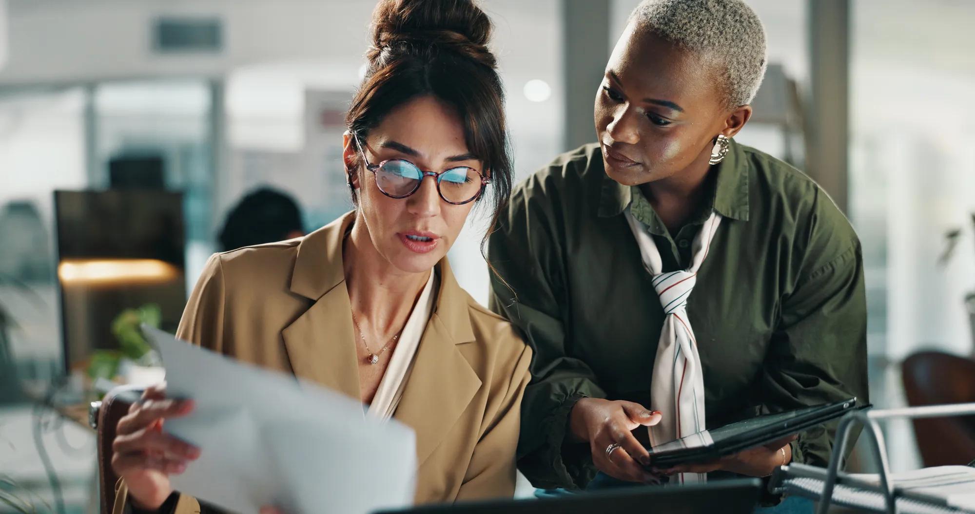 Women, tablet and team with documents in office for budget, review or report for project at finance company. Business people, tech and app with collaboration, feedback and asset management at agency.