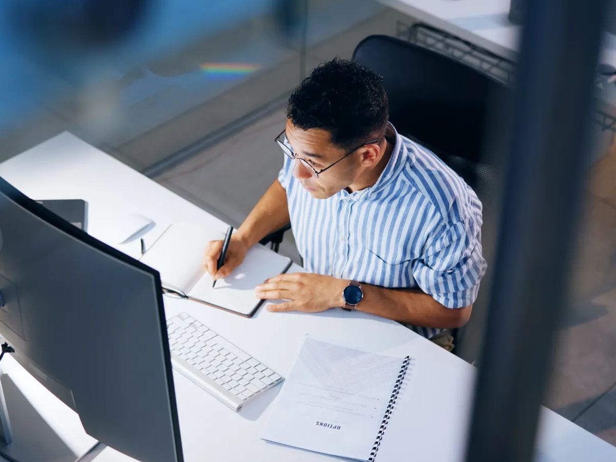 Writing, research and computer with business man in office for profit margin report, client review and advisory. Project, proposal and night with person and notebook for portfolio from above.