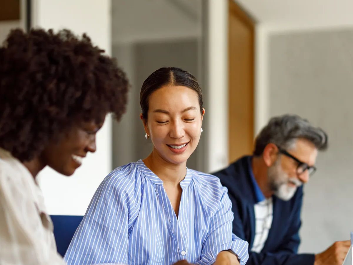Female professionals discussing business data and strategies in modern office while male colleague working in the background