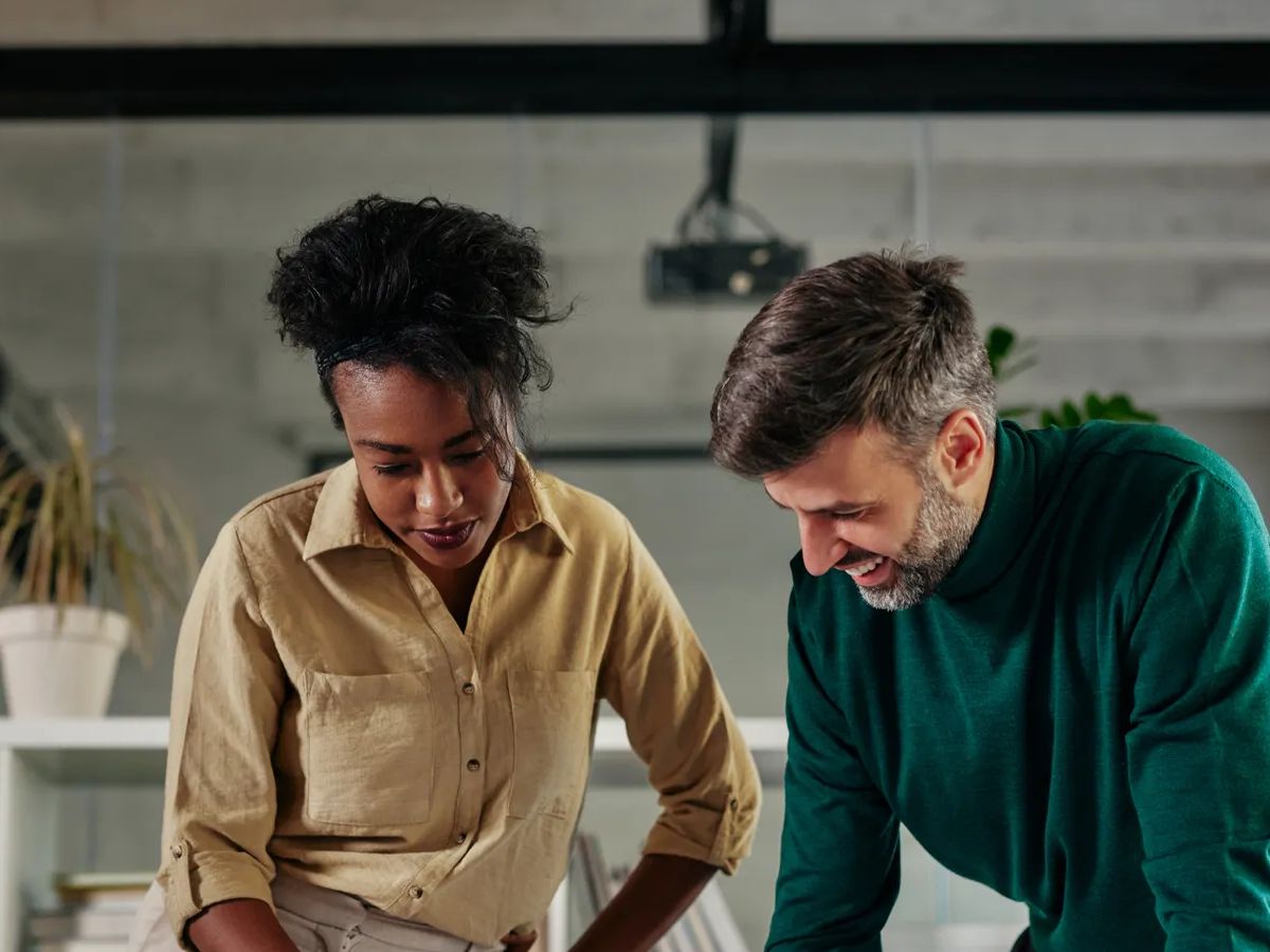 Two young multiracial business couple having a successful meeting in modern office. They are standing at the worktable and going through paperwork