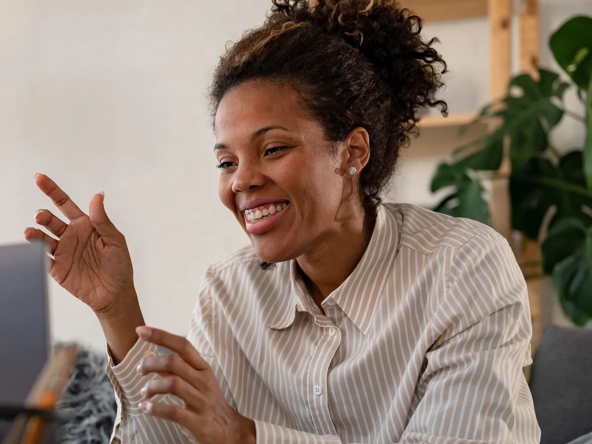 Young African ethnicity businesswoman working from home sitting in front of a laptop computer having a meeting over the internet. Woman freelance entrepreneur. 