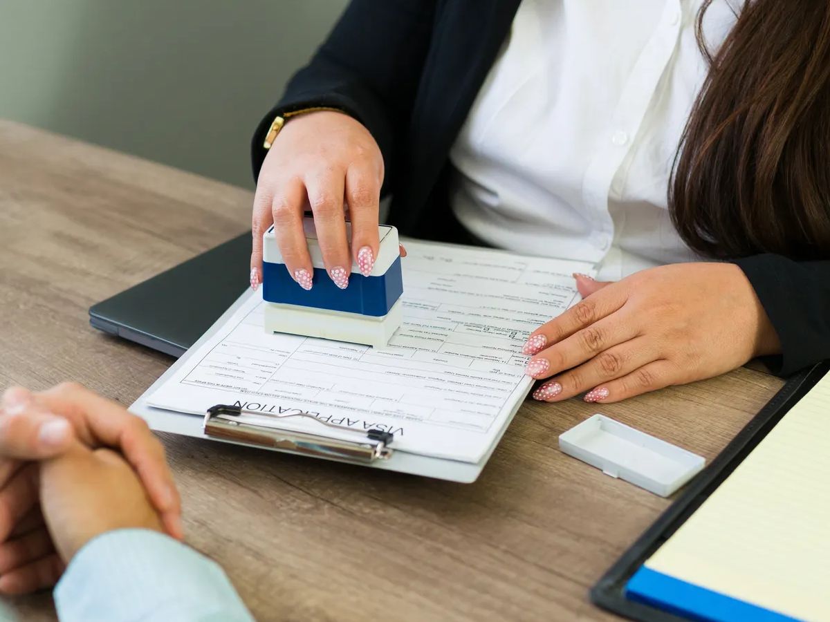 Immigration lawyer hand stamping a visa application or legal document for a client during a consultation in office