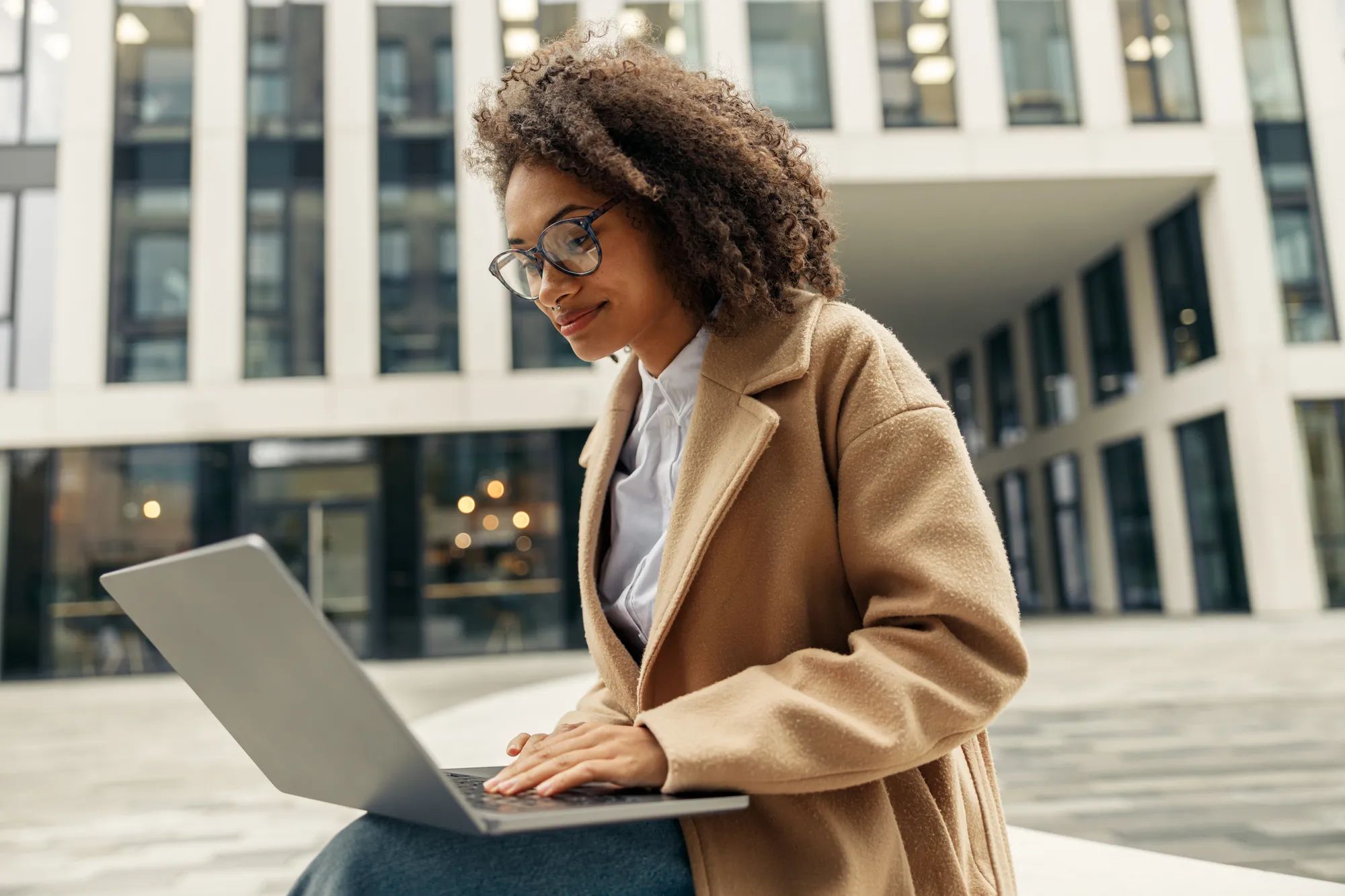 Business woman working laptop while sitting on background of office building. High quality photo