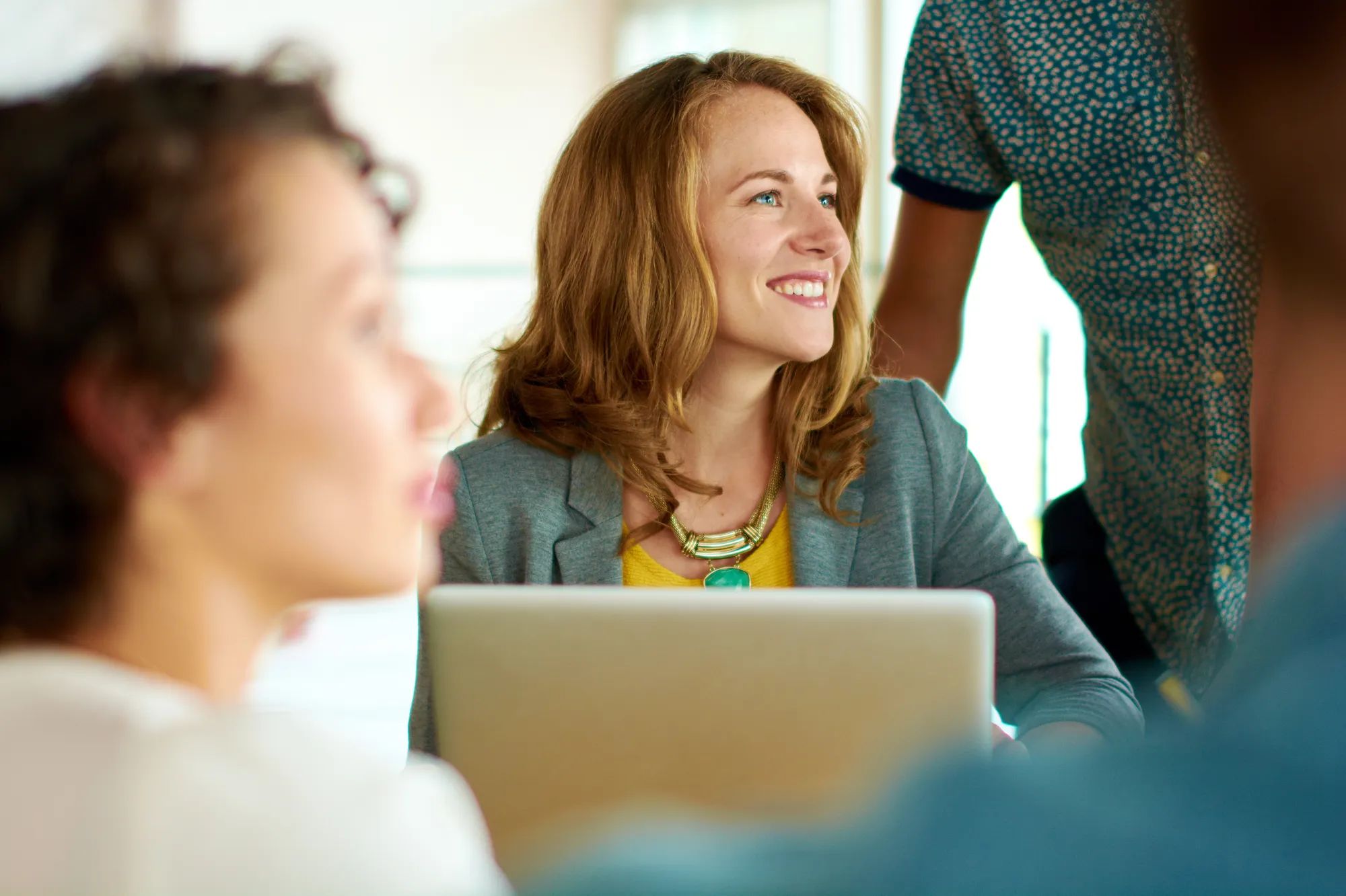 Group of young casual employees discussing a project while researching ideas in a digital touchscreen device and a laptop. 