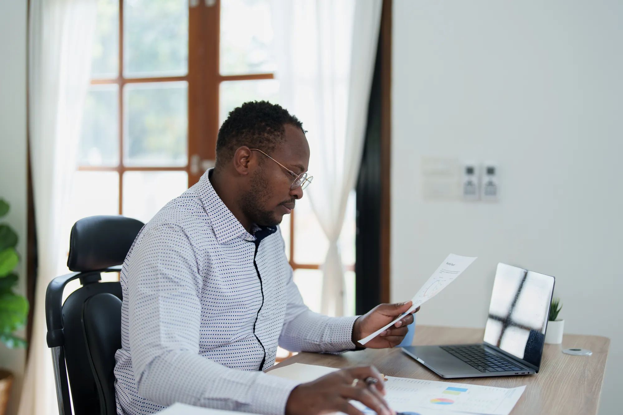 middle age man American African using calculator for calculating and laptop computer with planning working on financial document, tax, exchange, accounting and Financial advisor.