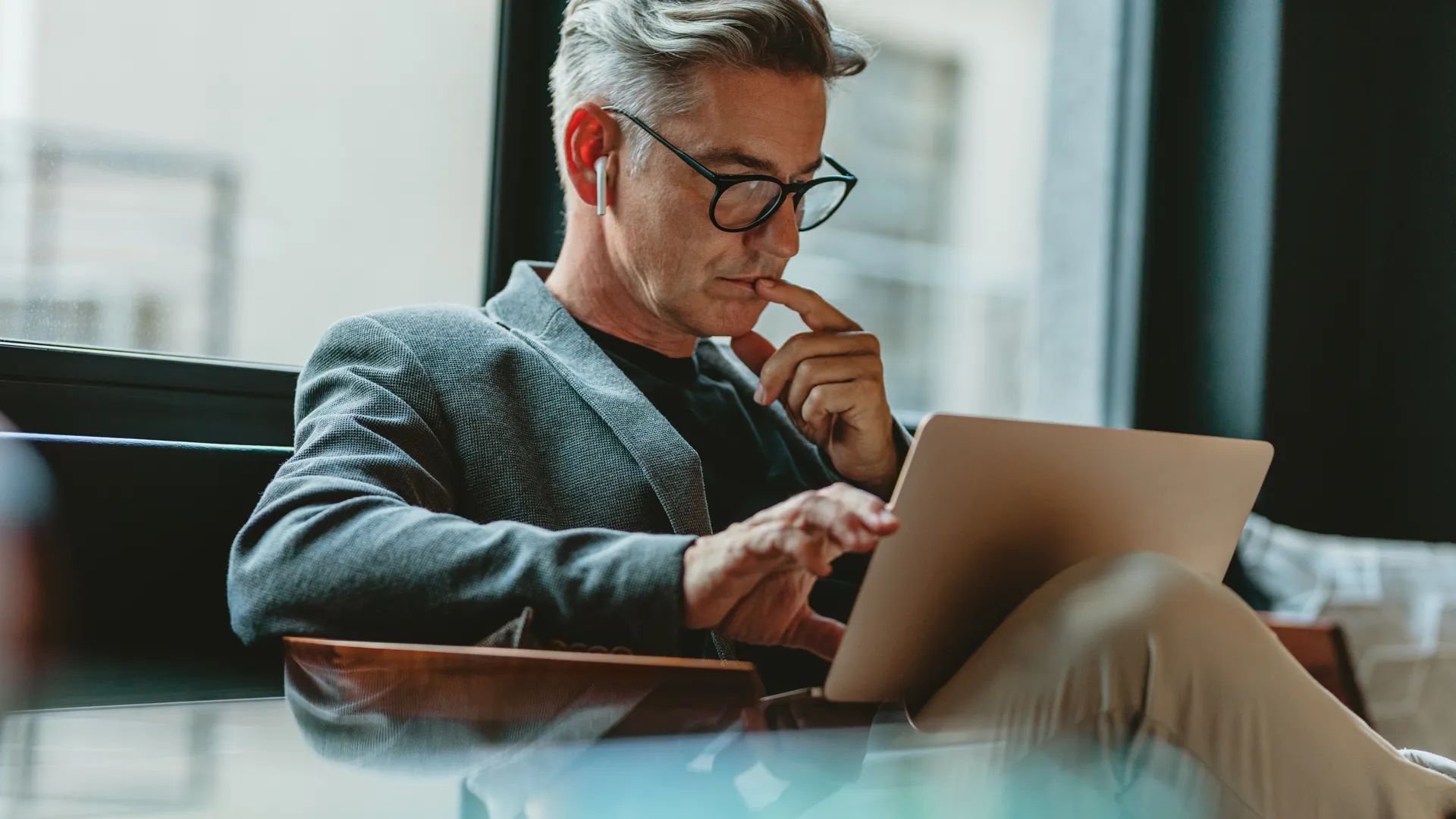 Businessman looking at laptop and thinking. Businessman reading emails on laptop in office lobby.