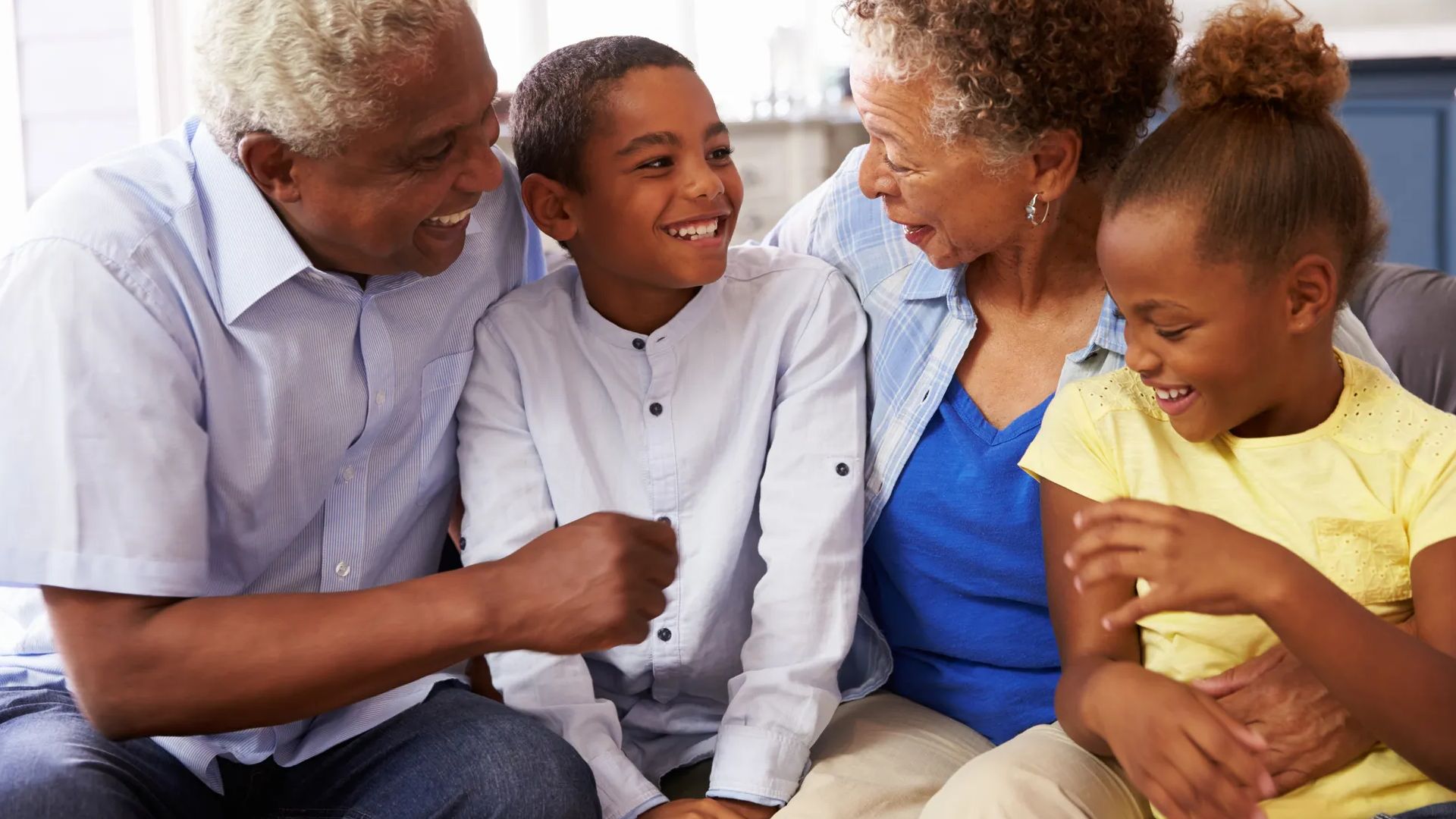 Grandparents and their young grandchildren relaxing at home