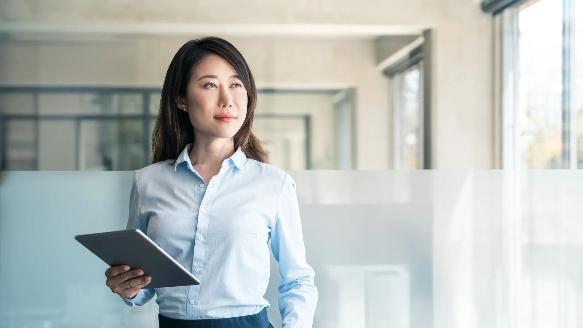 Dreaming thoughtful portrait of mature Asian woman business specialist female manager. Professional businesswoman CEO holding digital tablet using fintech tab for work in modern office. Copy space