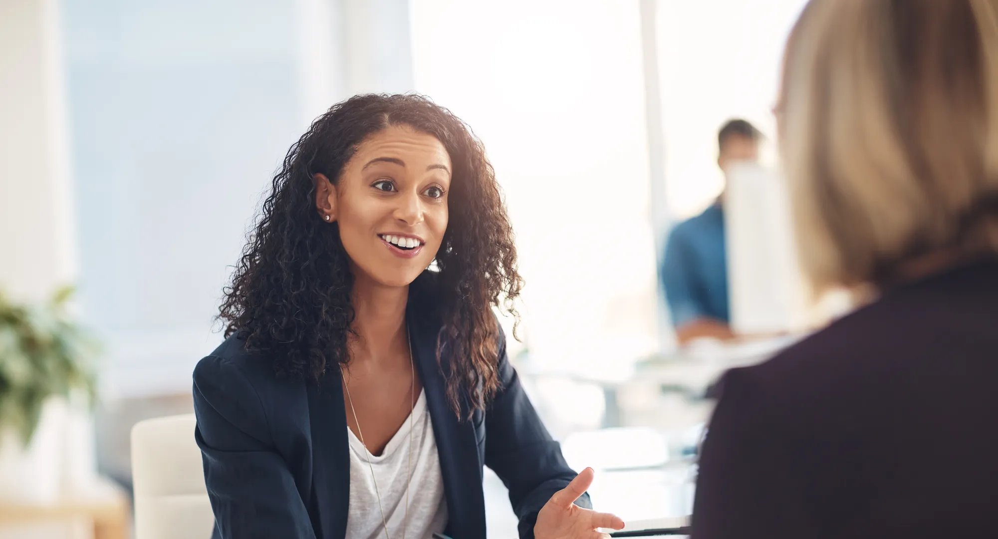 Interview with a happy, excited and confident human resources manager talking to a shortlist candidate for a job. Young business woman meeting with a colleague or coworker in her office at work.