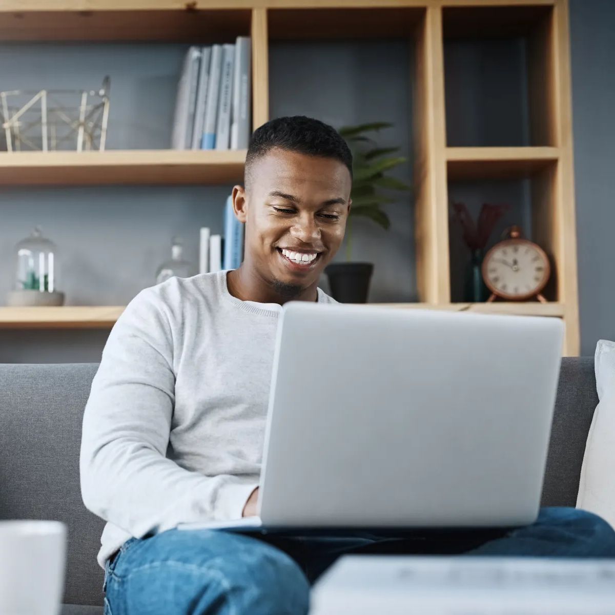 Shot of a handsome young man using his laptop while sitting on a sofa at home.