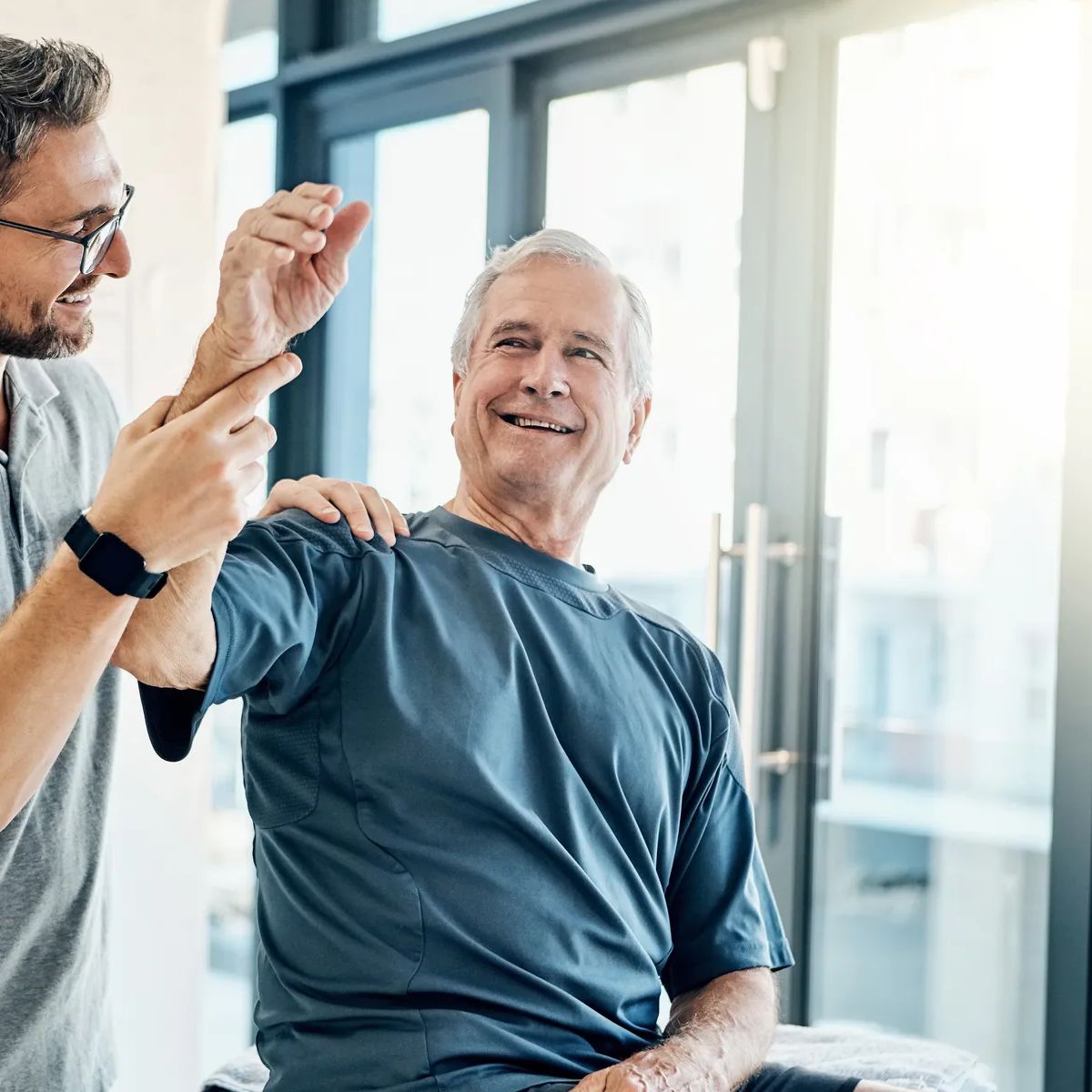 Physiotherapy, chiropractor and happy old man with arm pain for rehabilitation, consulting and exercise. Healthcare, physical therapy and person with patient for medical service, wellness and support.