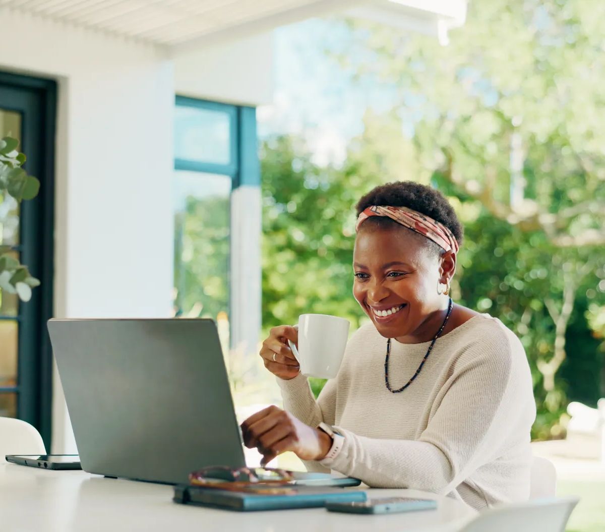 Coffee, laptop and smile with black woman in home for banking loan, wealth management and review. Online application, mortgage and budget report with person outdoor for drink, research and planning.