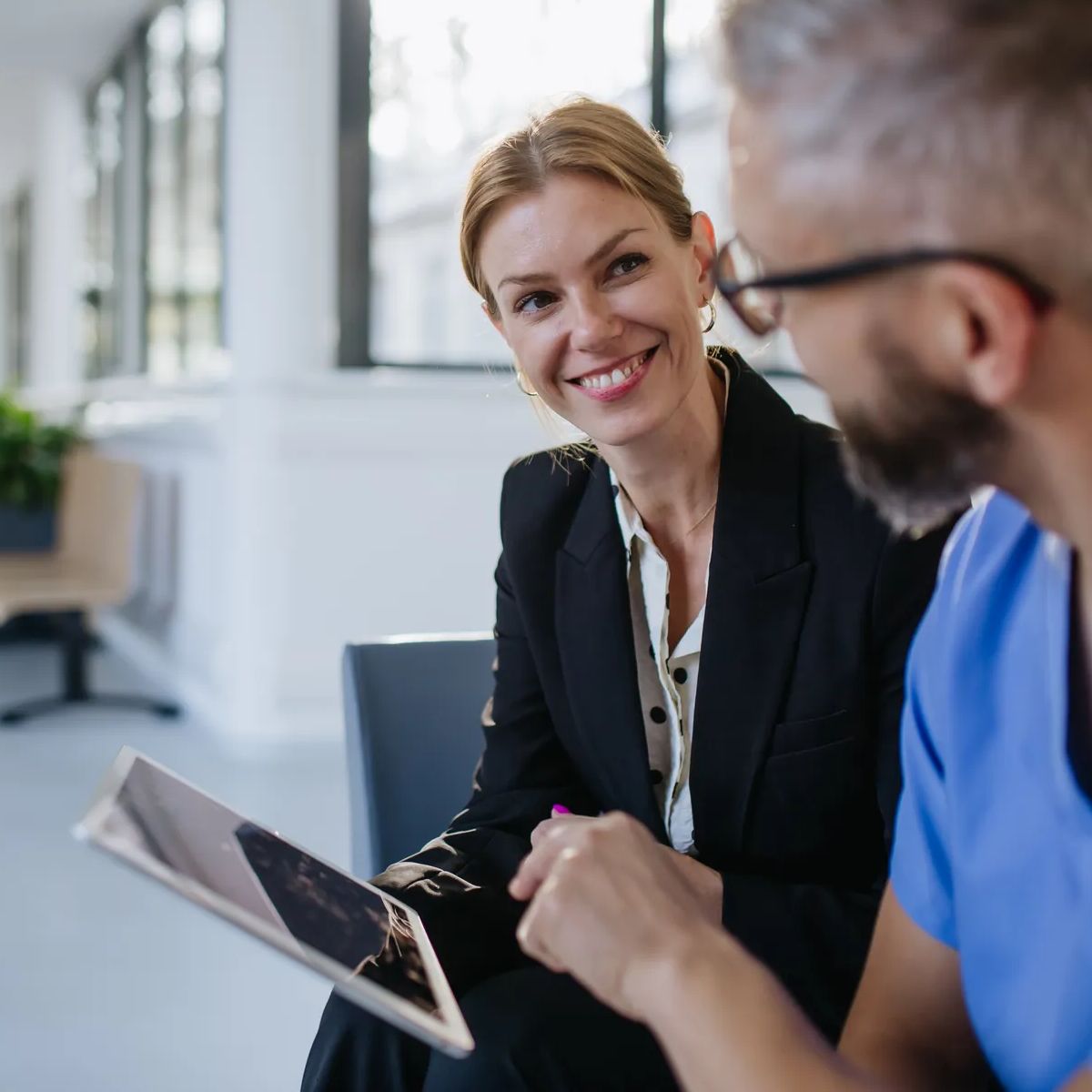 Pharmaceutical sales representative talking with doctor in medical building. Ambitious female sales representative presenting new medication, pills. Woman business leader.