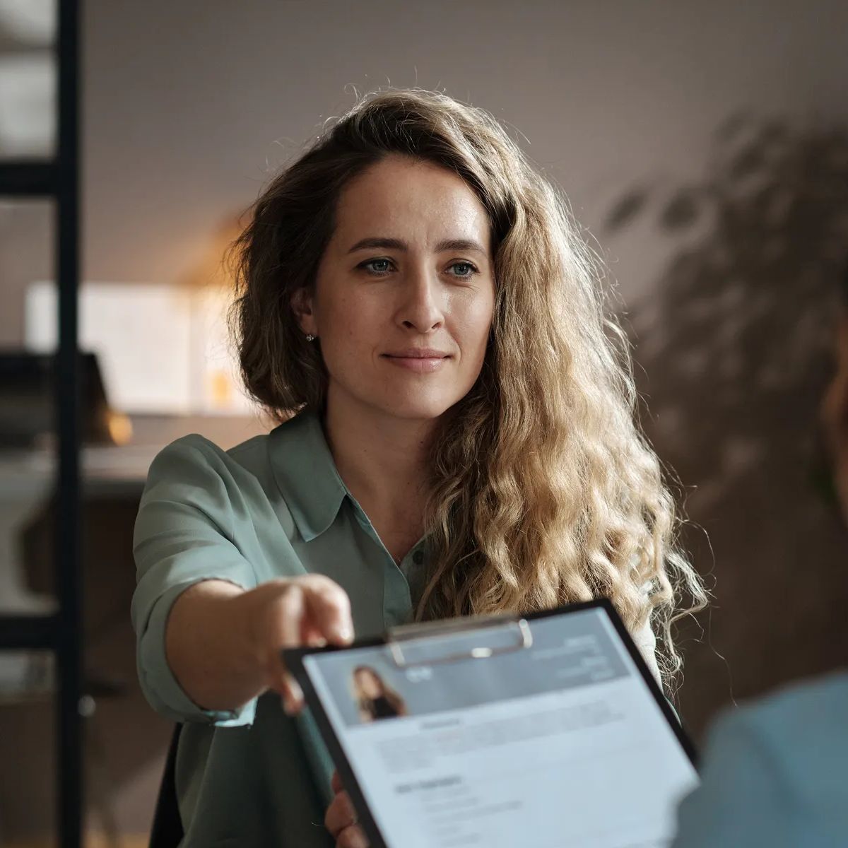 Young female candidate giving her resume to interviewer during job interview at office