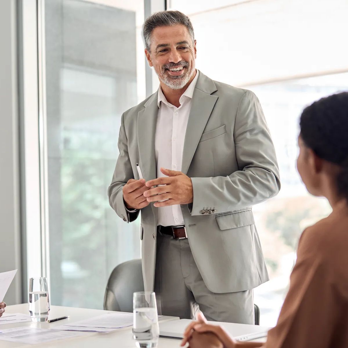 Busy older manager leader and company employees at business meeting discussing corporate management. International professional business people board team at boardroom office table.