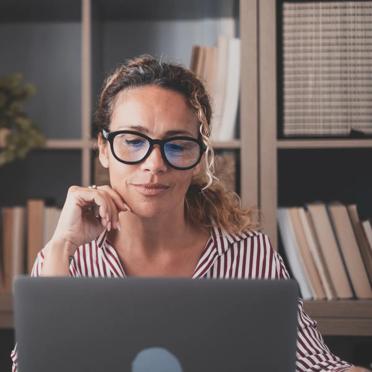 Happy young caucasian businesswoman smiling working online watching webinar podcast on laptop and learning education course conference calling make notes sit at work desk, elearning concept