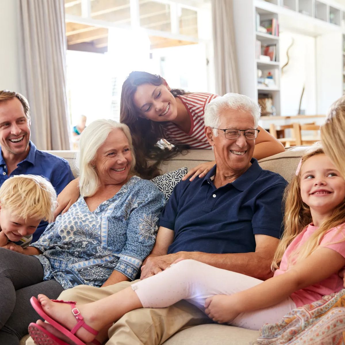 Multi-Generation Family Sitting On Sofa At Home Relaxing And Chatting