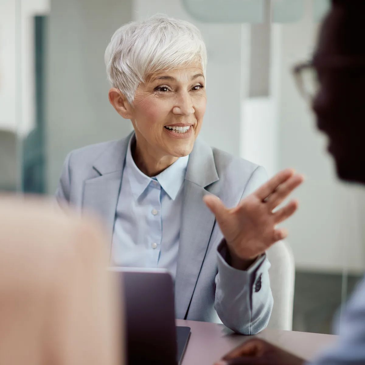 Happy mature insurance agent on meeting with her clients in office.