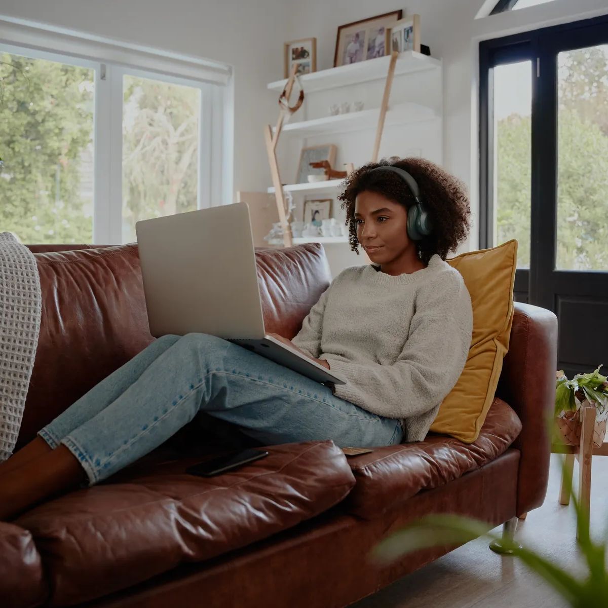 Woman relaxing on couch using laptop and headphones