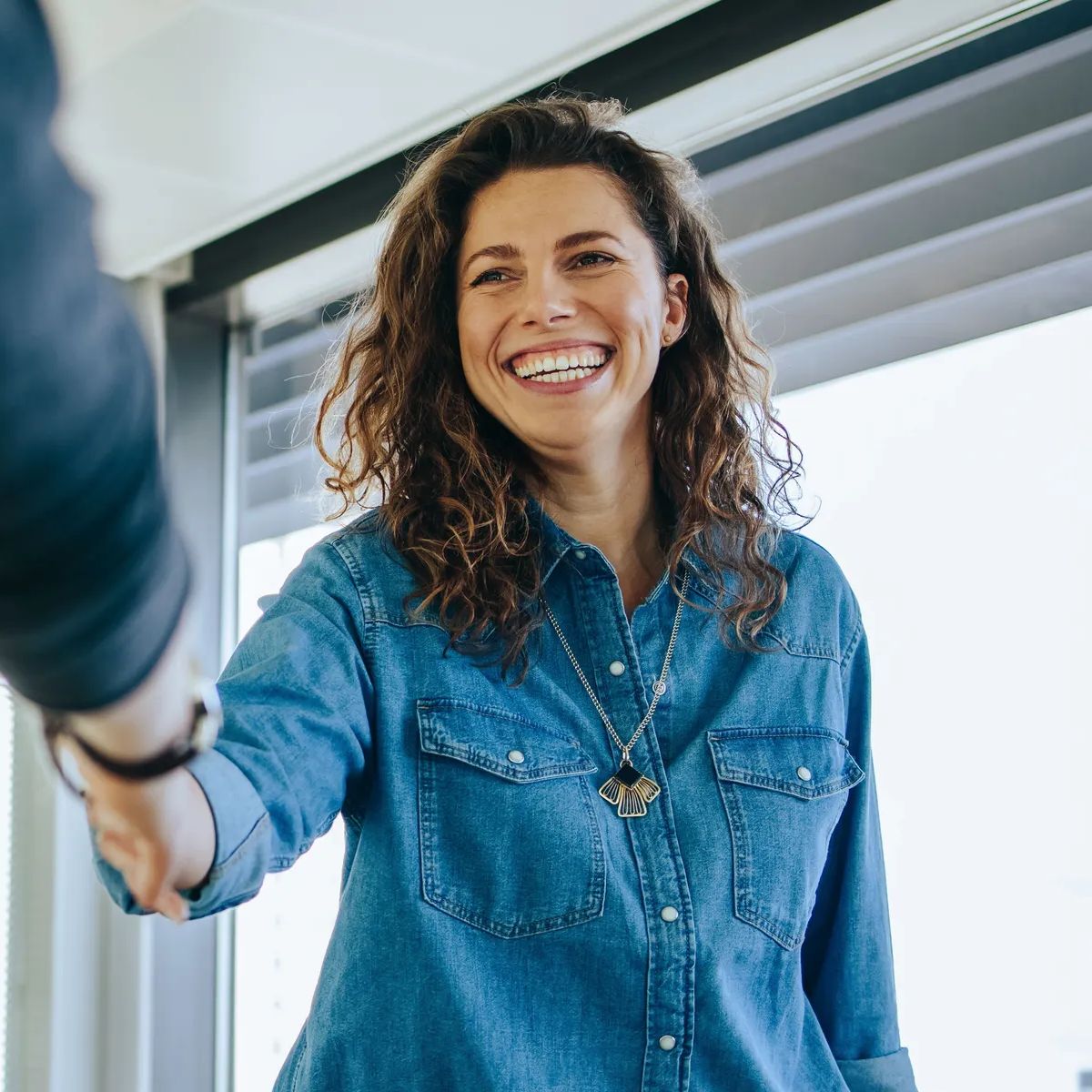 Businesswoman shaking hands with a job applicant in meeting room. Smiling female entrepreneur shaking hands with a male candidate for job interview.