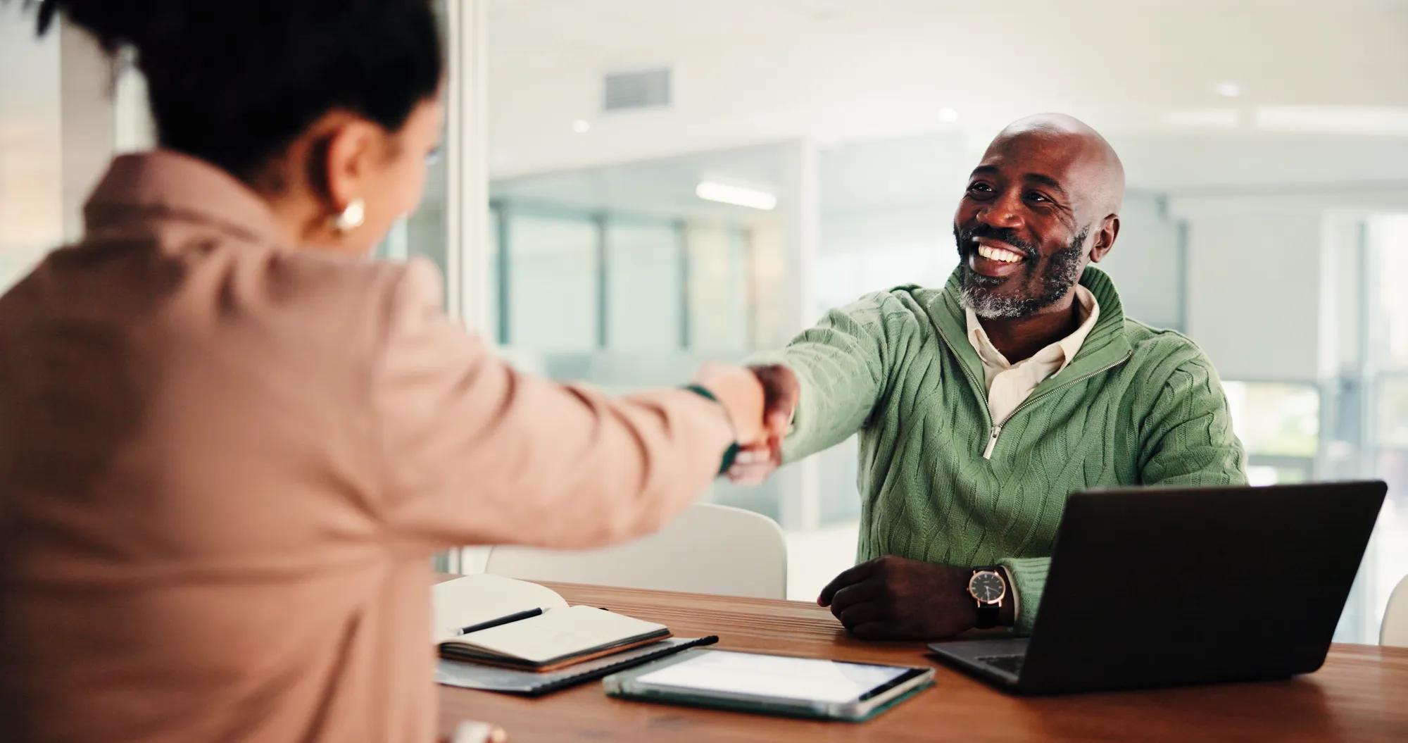 Business man, woman and handshake at interview for recruitment process, agreement or smile at office. People, manager and shaking hands with deal for onboarding, human resources or hiring at agency.