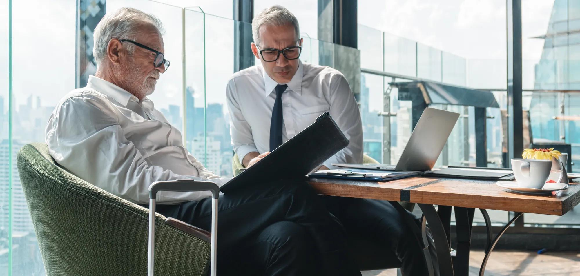 business background of senior business executive having business conversation with lawyer with laptop on table in office