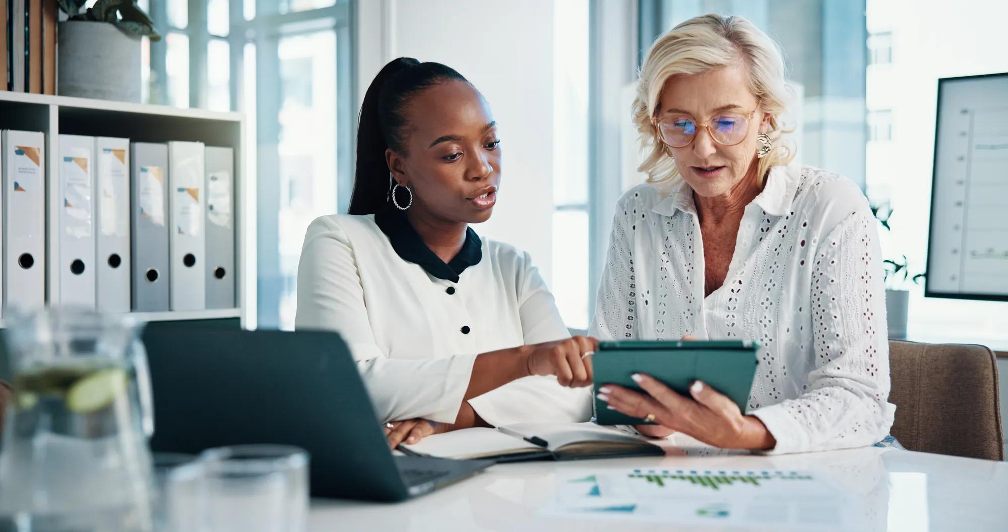An HR professional reviewing benefits documents on a laptop in a modern office setting.