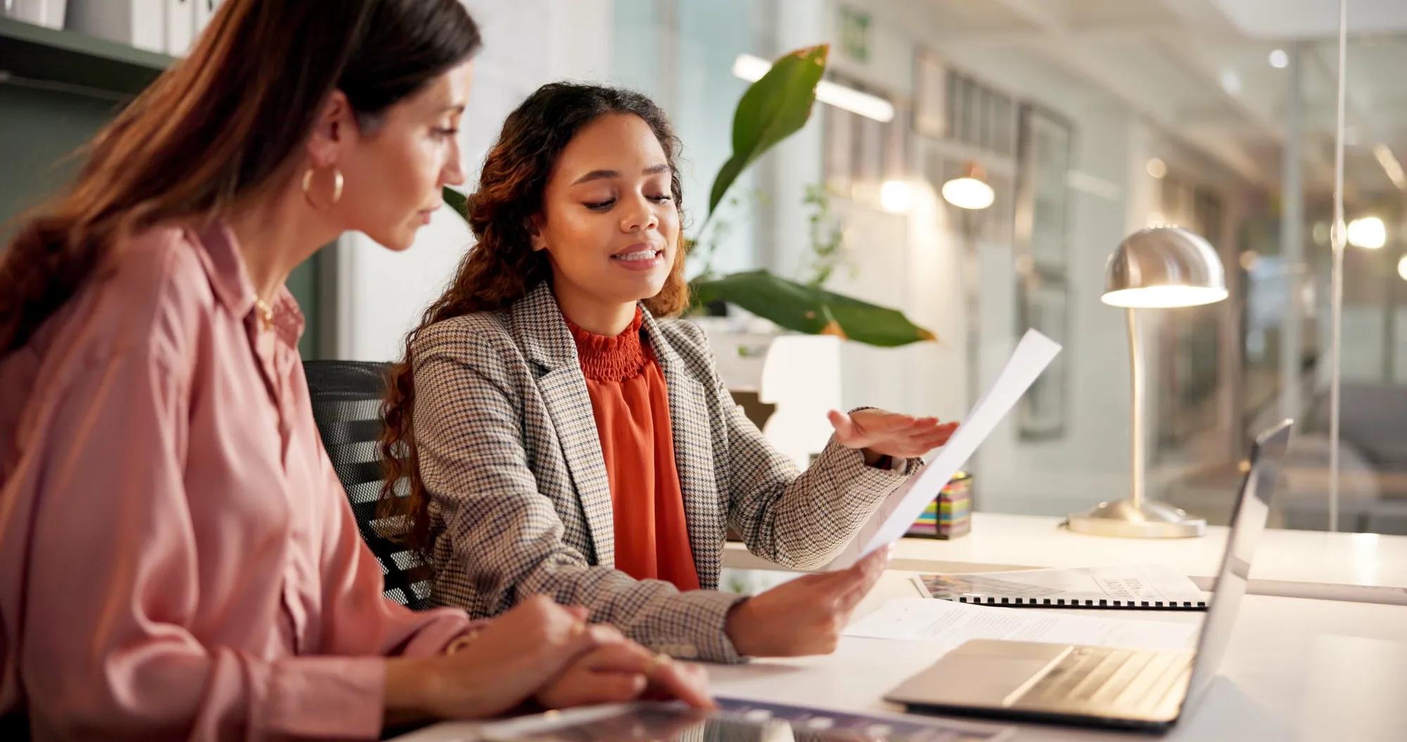 Planning, reading and financial advisor with client for document, investment discussion and tips. Business office, women team and talking with paperwork for policy review, laptop or corporate meeting.