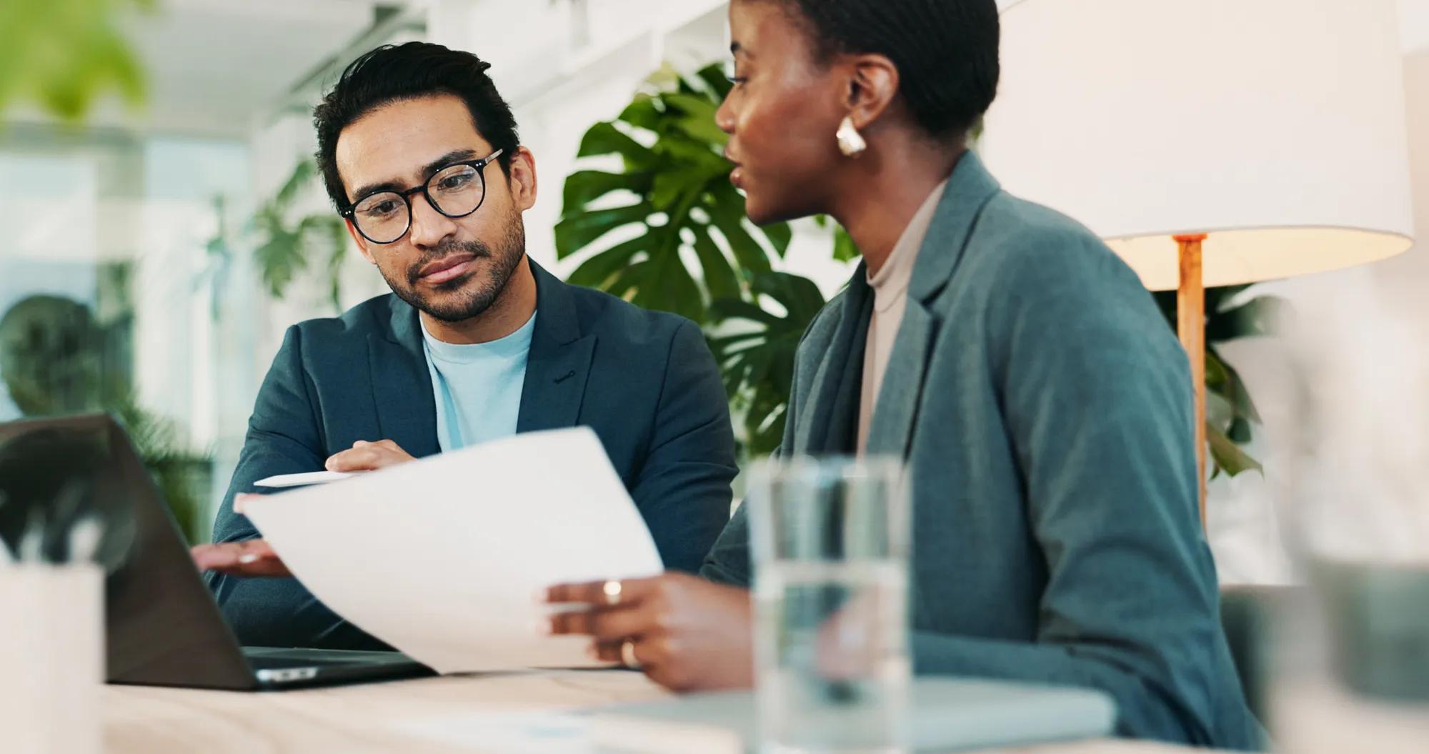 Two business professionals reviewing health plan transparency and compliance reporting requirements for employer-sponsored benefits plans.